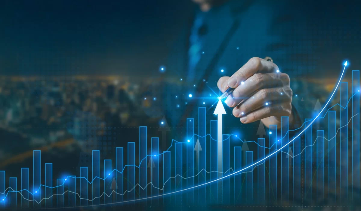 Hand touching a glowing upward arrow on a rising line chart over a city skyline at night