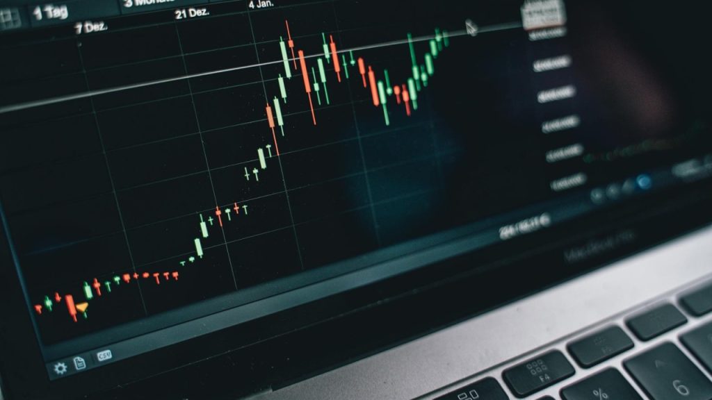 Close-up of a laptop screen showing a rising green and red candlestick chart