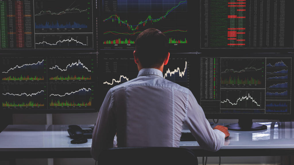 Professional trader monitoring real-time financial charts on multiple monitors
