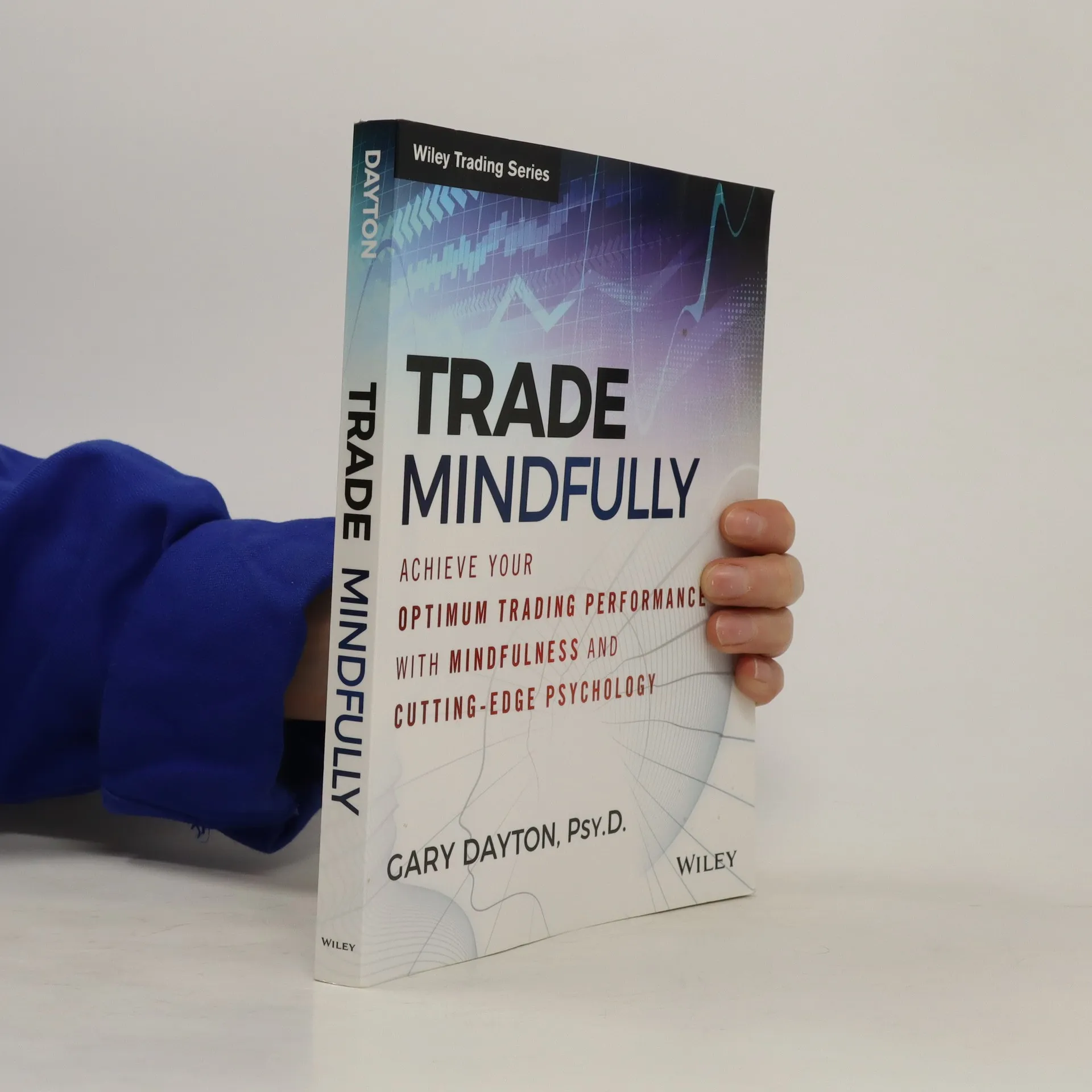 Hand holding a copy of Trade Mindfully by Gary Dayton, a Wiley book on trading performance and mindfulness
