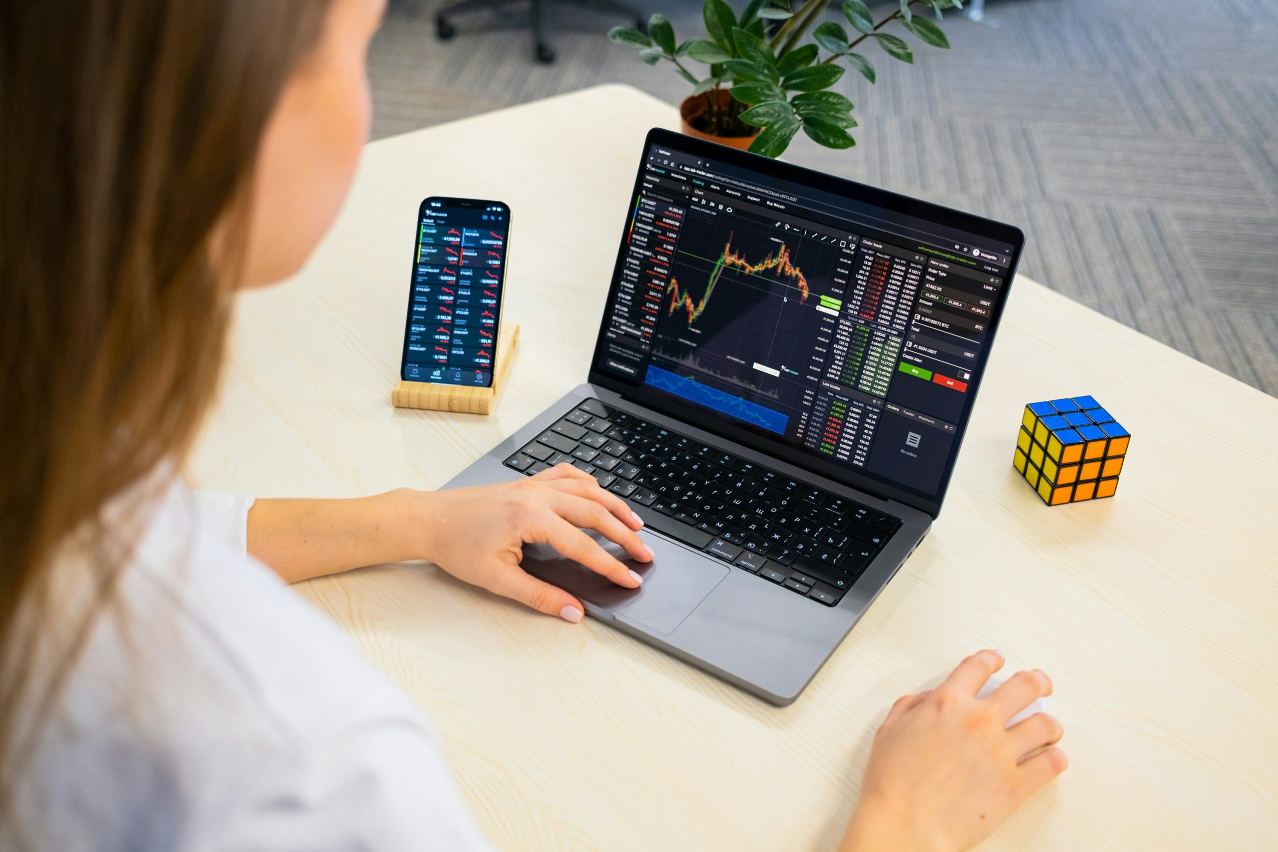 A confident woman trading on multiple screens, representing Sarah's successful journey with AI Prop, achieving financial freedom through AI coaching and flexible rules.
